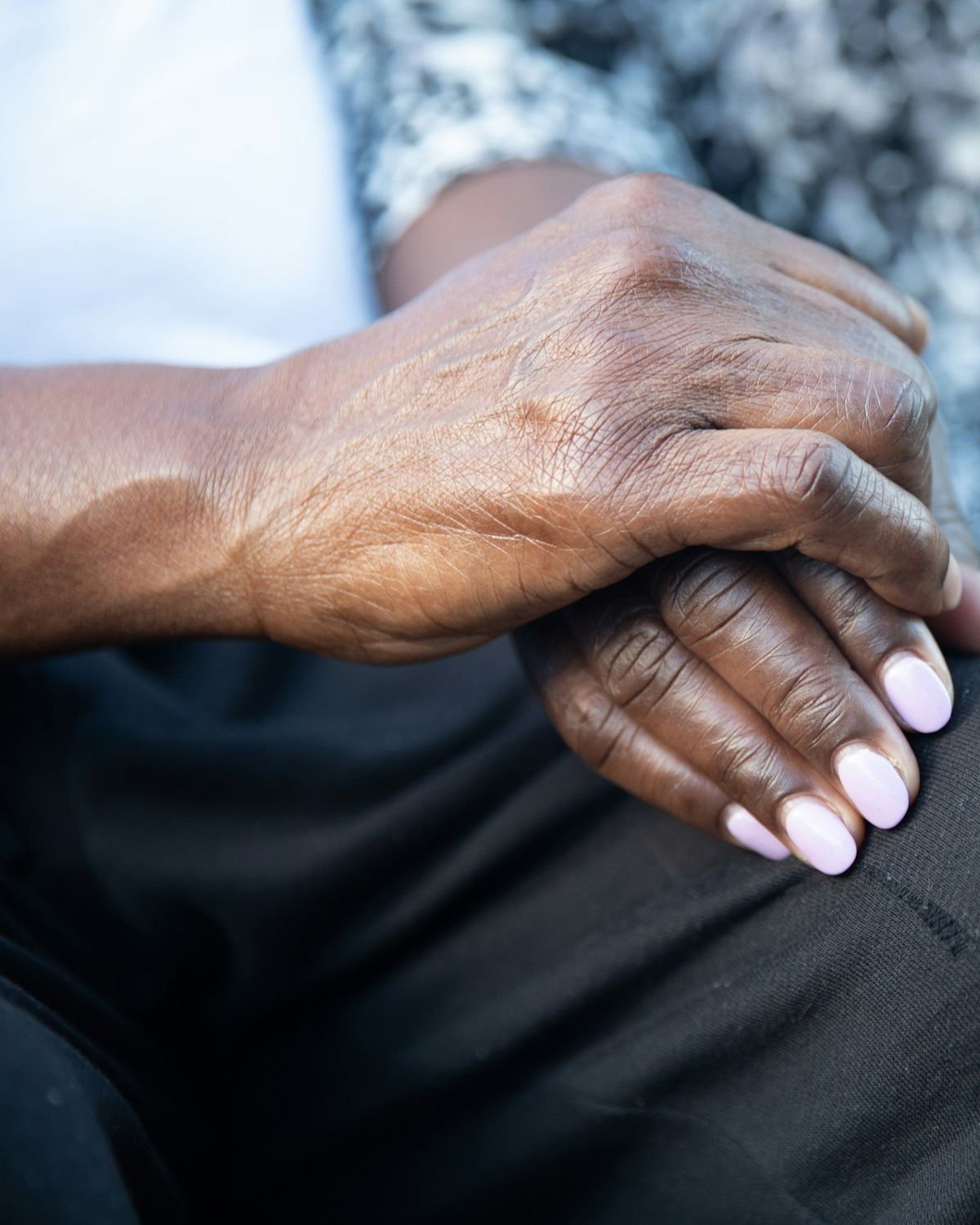 Mãos de uma pessoa idosa apoiadas no colo, em ambiente tranquilo