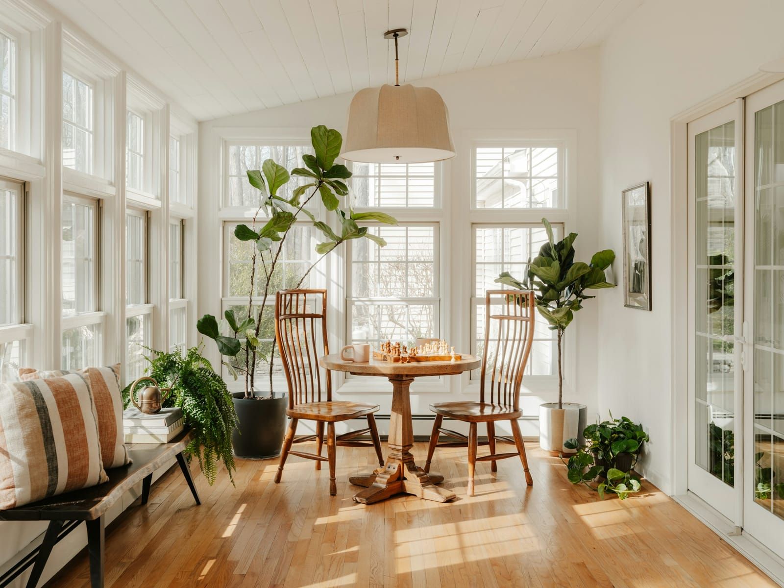 Sala luminosa com mesa de madeira e plantas junto à janela